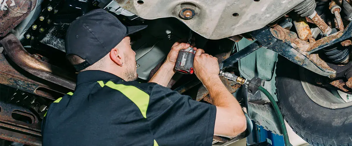 Technician working underneath a vehicle at Al’s D&I Auto Repair.